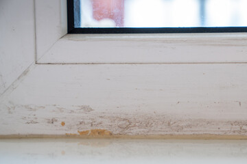 Part of dirty window frame after installing plastic windows and removing duct tape. Need special cleaners for difficult stains. Damaged frames with glue residue plaque on surface after renovation.