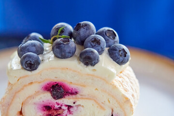 Sweet roll with blueberries. White dessert on a white plate