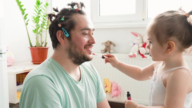 A happy father and child having fun with makeup, with the dad being supportive and enthusiastic about his child's creativity. Daddy Daycare A Bearded Dad and His Child Share a Funny Moment