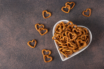 Salty heart-shaped crackers in a heart-shaped plate on a brown background, Snack for Valentines Day