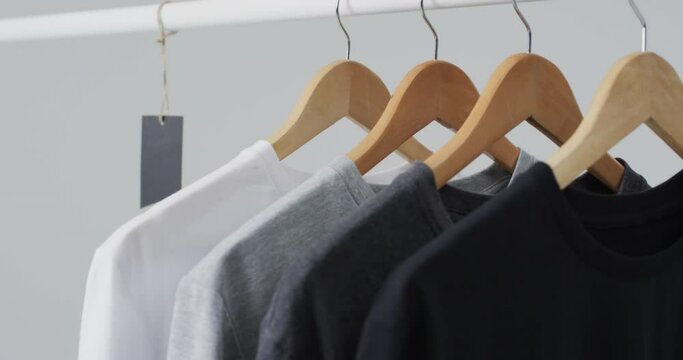 Video of four t shirts on hangers and copy space on white background