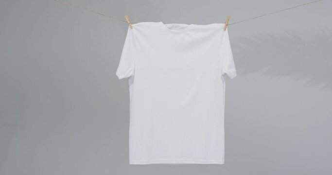 Video of white t shirt with clothes pegs and copy space on grey background