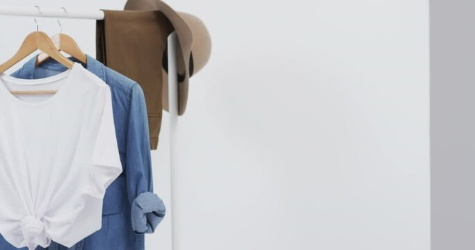 Video of white and denim t shirt on hangers, hat and copy space on white background