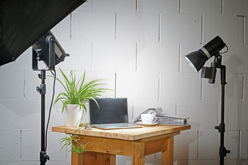 Small table top photo studio in a garage with a wooden board for the objects, lights and stands,...