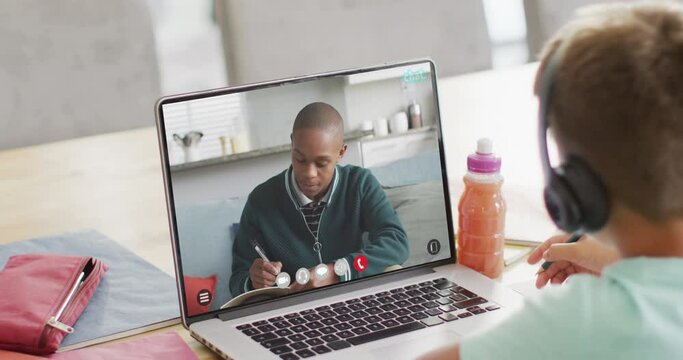 Composition of caucasian boy on laptop online learning with african american schoolboy