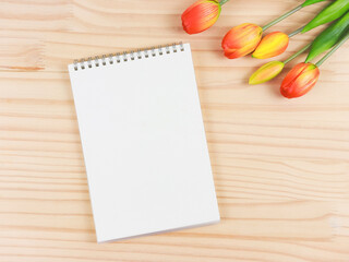 flat lay of opened blank pages notebook or diary with tulips bouquet on wooden table background  with copy space.