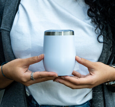 A woman with a white wine tumbler mockup, impressively showcasing your brand's charm and elegance