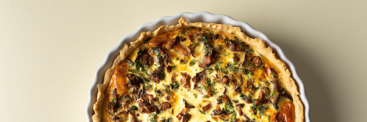 Homemade quiche with seasonal forest mushrooms Chanterelles in a round shape on a yellow background, banner with pie