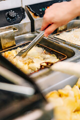 Chef cooking delicious potato chips in hot oil on kitchen