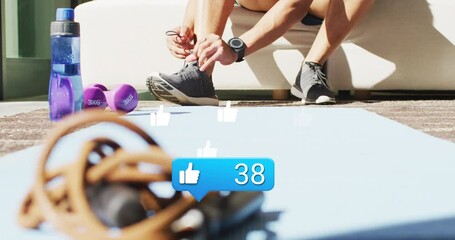 Animation of like icon and numbers over african american male athlete tying shoelace - Powered by Adobe