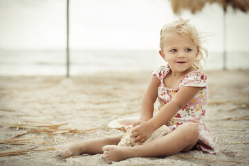 Two and half years old girl posing on sea beach with giant shell