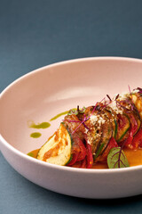 Vegetable ratatouille in a plate on a dark background.