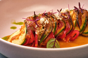 Vegetable ratatouille in a plate on a dark background.