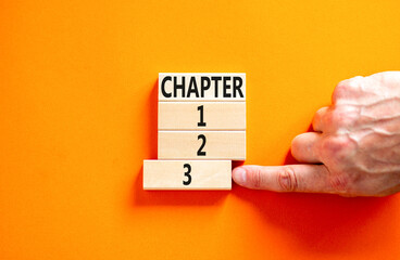 Time to chapter 3 symbol. Concept word Chapter 1 2 3 on wooden block. Businessman hand. Beautiful orange table orange background. Business planning and time to chapter 3 concept. Copy space.