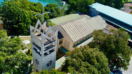 Church. Aerial view of the Catholic Church and the bell tower with a cross among the dense green...