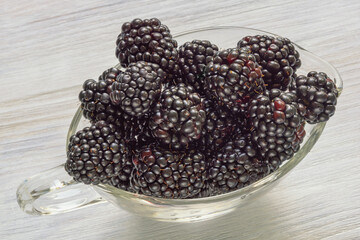 Berries. Fresh ripe blackberries in glass bowl on rustic table