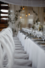 Wedding decor, table setting with white dishes and glass glasses, against the background of lanterns