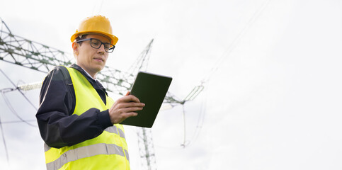 Engineer with digital tablet on a background of power line tower