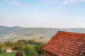 Fototapeta na wymiar Red tiled roof of a house in autumn mountains