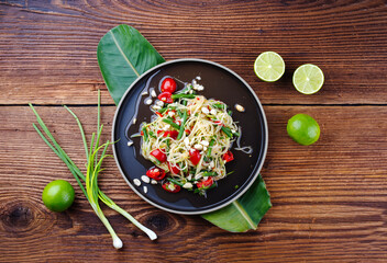 Traditional Thai green papaya som tam salad with green papaya slices, cherry tomatoes and beans in...
