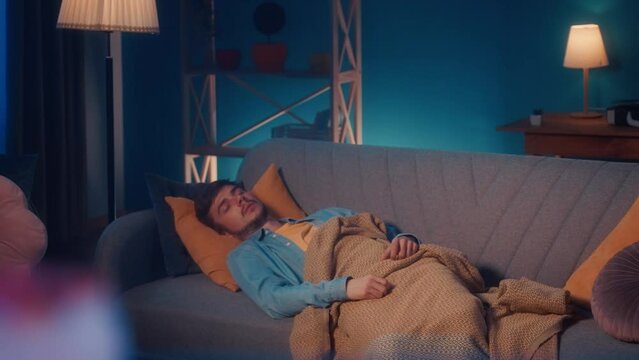 Refrigerator shelves with unhealthy food, inside view. The refrigerator door opens, the man sleeps on the couch and in his sleep reaches for the refrigerator, for food.