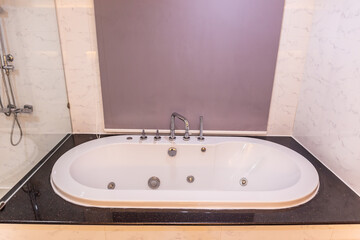 White bathtub with warm lighting against with hot and cold water faucet