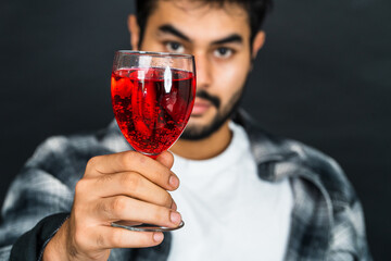 Expertly staged, the image captures a man showcasing a red colored drink, ready to enhance your...