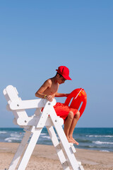 Boy lifeguard next to the watchtower on the beach