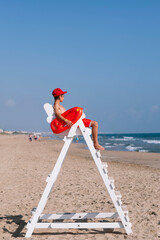 Boy lifeguard next to the watchtower on the beach