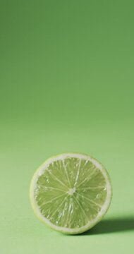 Vertical video of sliced lime with copy space over green background