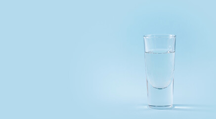 Glass of pure sparkling water on light blue background. Free space for text