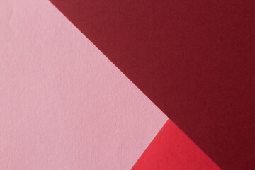 Paper in three shades of red lies on the table, creating a geometric composition