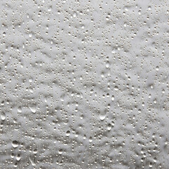 Water droplets on a clean window pane against a pure white background
