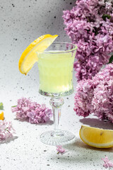 traditional liqueur limoncello with blooming lilac on a light background