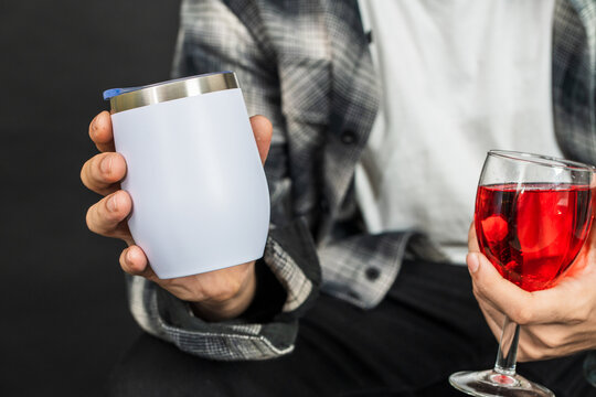 Skillfully arranged, the mockup showcases a man elegantly displaying a white blank tumbler and a glass of red wine in the other hand, perfect for adding sophistication to your mockup projects
