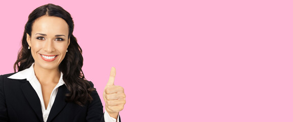 Businesswoman in black confident suit showing thumbs up gesture, over rose pink color background. Happy smiling gesturing brunette woman at studio. Business concept photo.