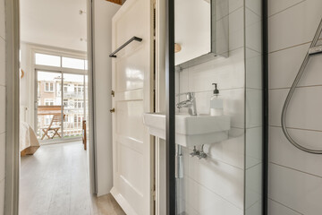 a bathroom with white tiles on the walls and wood flooring in front of the shower stall, which has been used as a