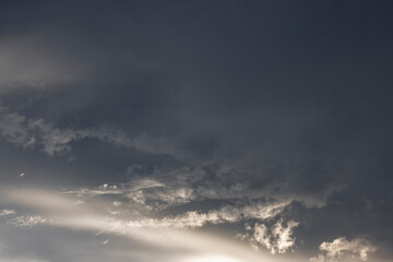 Storm clouds illuminated by sunlight in a blue sky before rain