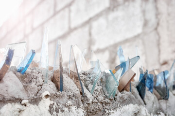 Close up picture of shards of glass on a wall, used to secure private property, selective focus. - 626270844
