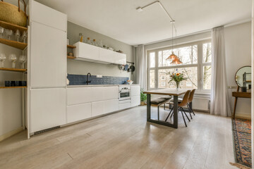 a kitchen and dining area in a house with white cabinets, wood flooring and wooden shelves on the wall
