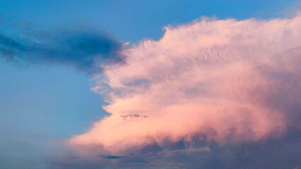 a large pink cloud lit by the sun on a blue sky