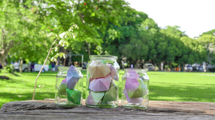 Paper hearts in glass bottles on wooden floor with blurred trees background concept for cheering...