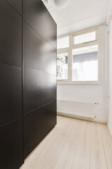 an empty room with wood flooring and black cabinetd cupboards on the wall in front of the door