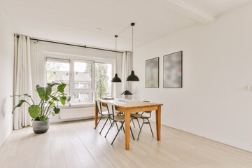 a dining room with white walls and wood flooring there is a wooden table, two black chairs and a large window