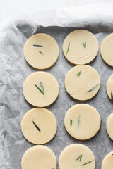 Top view of cut out raw rosemary sugar cookie dough, rosemary cookie dough about to be baked, process of making rosemary sugar cookies