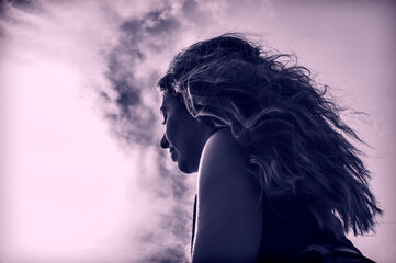 Close-up of a girl with long hair portrayed from below with the sky as the background