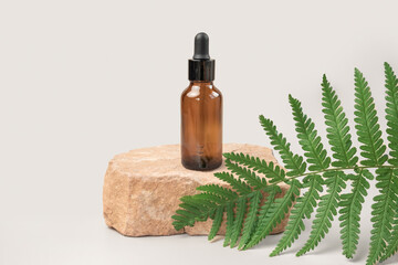 Naklejka premium Dark amber glass bottle standing on stone. Natural skin care SPA beauty product design. Mineral organic oil cosmetics. Gray background. Mock-Up. Oily pipette. Face and body treatment. Front view stand