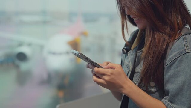 Happy asian tourist woman using mobile smartphone with backpack traveling between waits for flight in Airport Terminal, Browse Internet, flight check in, Tourist journey trip concept