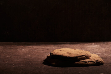 Brown stone podium display on black background, mockup. Decorative textured stand for beauty...