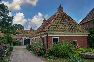 Fototapeta na wymiar Characteristic streetscape in a traditional northern-Dutch village, with historic houses and small gardens with colorful flowers. Tinallinge, province of Groningen